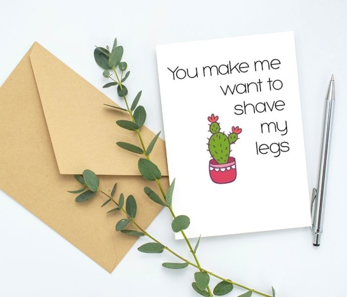 Greeting card and envelope sitting on a table with a pen. The card says "You make me want to shave my legs" next to a picture of a cactus in a pot.